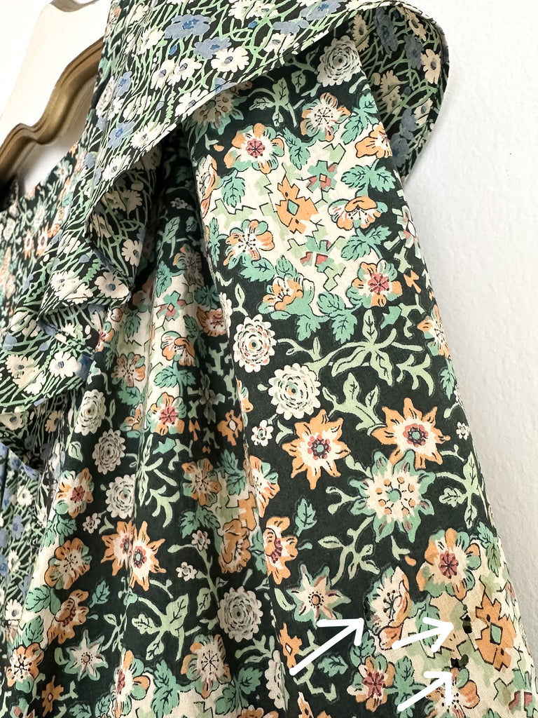 Floral fabric with green, orange, and white flowers on a black background